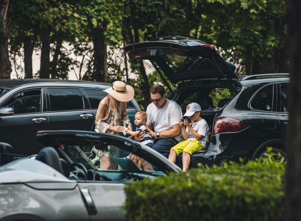 Modern American family with children sitting by their SUV, representing trust, safety, and the protection offered by the best auto insurance companies in the USA.